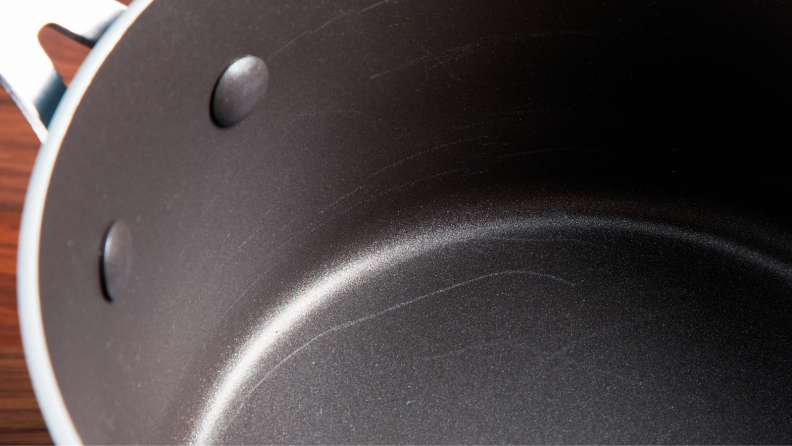 Dark nonstick interior of pot with multiple scratches.