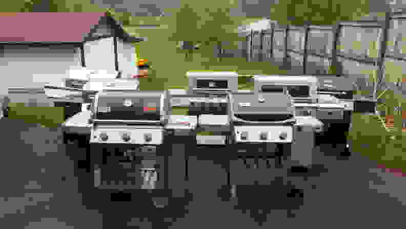 Seven gas grilled set up beside each other in a backyard.