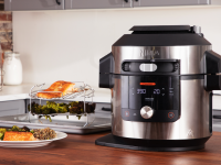 A Ninja Foodi pressure cooker sits on a kitchen countertop surrounded by food.