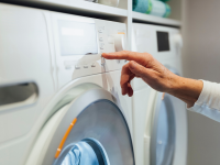 Person pressing buttons on washer machine.