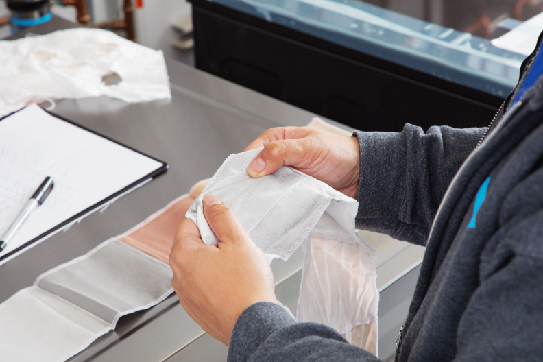 A person holding a piece of cloth, testing the washing machine.